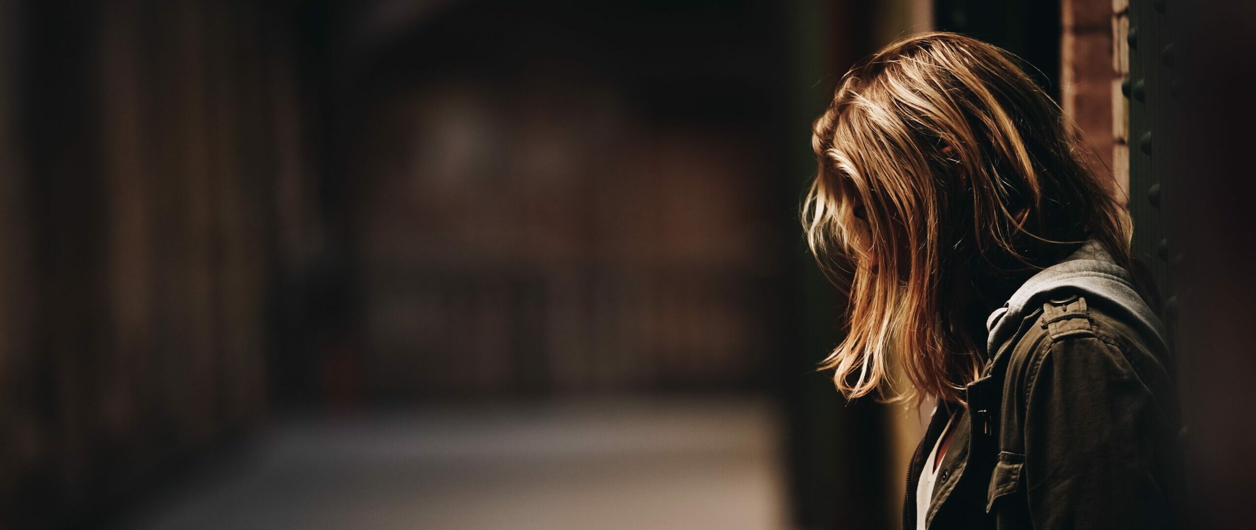 Female leaning against the wall looking down in a hallway with blurred background in Alcatraz Island